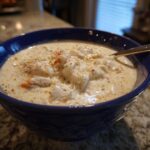Close-up of a rich, creamy bowl of she crab soup topped generously with white crab meat and spices.