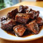 Close-up of tender, cubed crockpot steak coated in a thick, dark, savory sauce with visible spices.