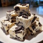 A stack of creamy white Oreo fudge squares loaded with crushed chocolate sandwich cookies.