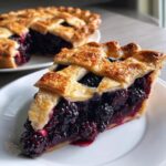Close-up of a generous slice of amazing blackberry pie showing juicy filling and a golden flaky lattice crust.
