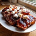 Close-up of thick slices of amazing candied yams covered in a dark, glossy glaze and topped with mini marshmallows.
