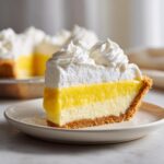 A perfect slice of amazing 1-step lemon pie featuring a graham cracker crust, bright yellow filling, and topped with fluffy whipped cream.