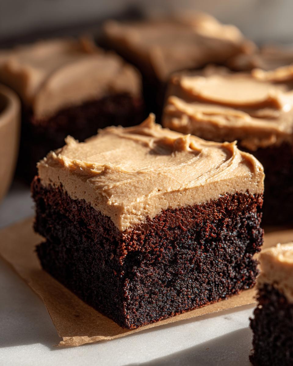 Close-up of a thick, dark chocolate banana bread brownies square topped with creamy peanut butter frosting.