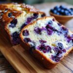Close-up of a thick slice of Blueberry Cream Cheese Bread showing moist crumb, purple blueberries, and cream cheese pockets.
