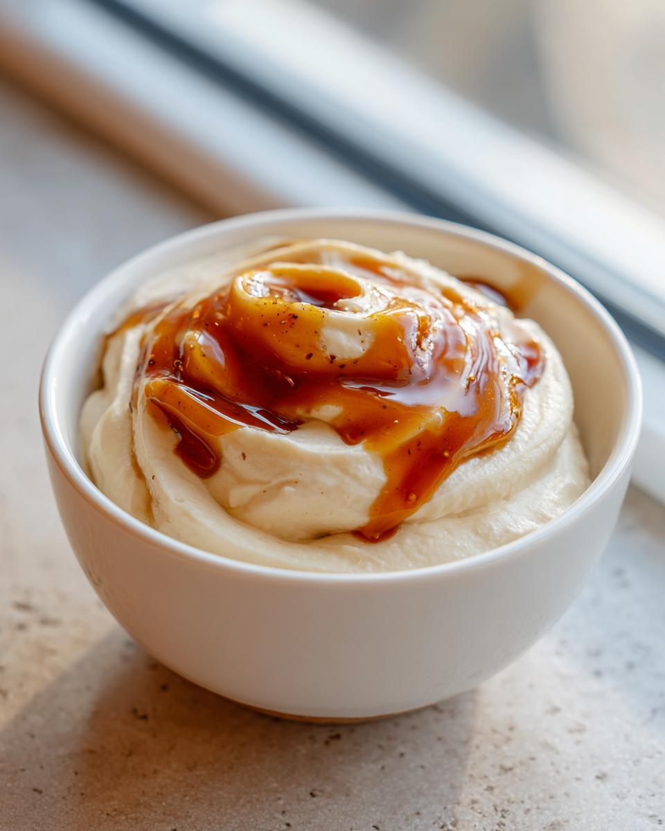 Close-up of a creamy, swirled whipped ricotta dip topped with a rich caramel sauce.