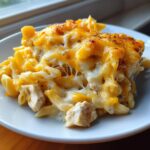 A serving of cheesy chicken pasta with melted, gooey cheddar and white cheese topping.