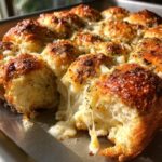Close-up of cheesy hawaiian roll garlic bread, showing melted cheese stretching as a roll is pulled apart.