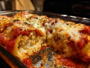 Close-up of baked cheesy stuffed shells overflowing with ricotta filling and topped with melted mozzarella and marinara sauce.