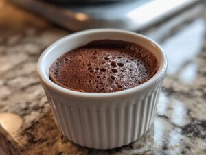 Close-up of rich, airy chocolate mousse served in a white, fluted ramekin.