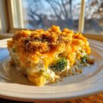 A close-up of a creamy slice of Chicken Divan casserole topped with melted cheddar and crunchy breadcrumbs.