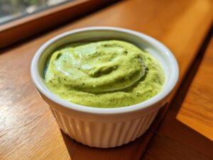 Close-up of vibrant green, creamy cilantro lime sauce served in a small white fluted ramekin.
