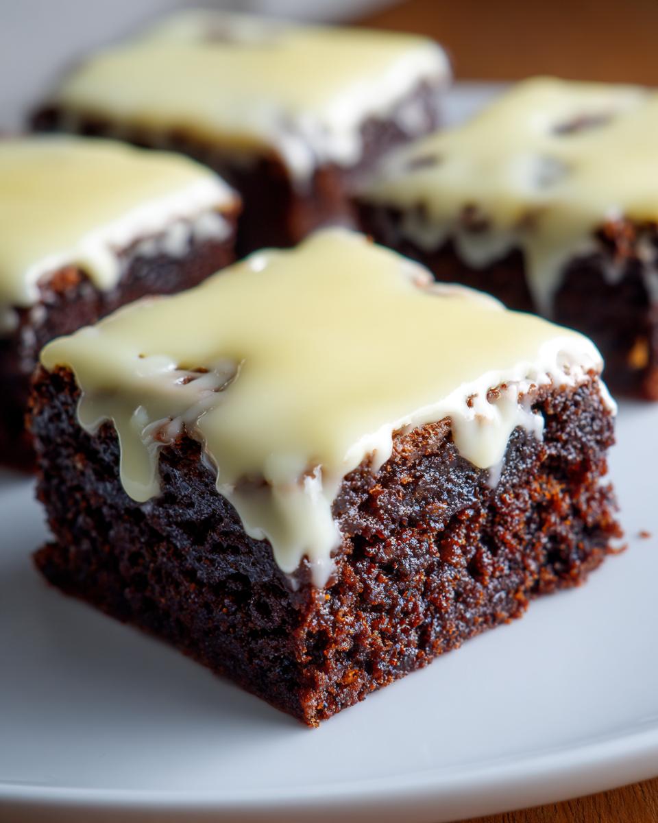Close-up of a fudgy, dark chocolate Lemon Brownies square topped with a thick, dripping white lemon glaze.