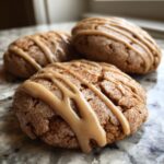 Close-up of three soft applesauce cookies topped with cinnamon sugar and a thick caramel glaze drizzle.
