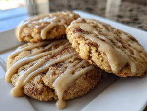 Close-up of three soft applesauce cookies topped with cinnamon sugar and a thick caramel-colored glaze.