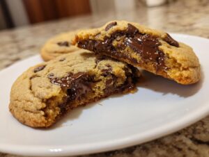 Close-up of a sourdough chocolate chip cookie broken in half, showing melted, gooey chocolate chips inside.
