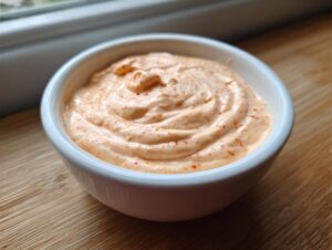 Close-up of creamy, orange-tinted homemade big mac sauce swirled in a small white dipping bowl.
