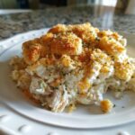 A close-up of a serving of creamy hot chicken salad casserole topped with golden, crunchy breadcrumbs.
