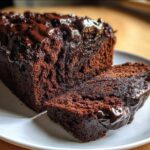 Close-up of a slice of rich, dark hot fudge brownie bread topped with dripping chocolate glaze.