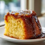 Close-up of a moist slice of bacardi rum cake topped with a rich, dark rum glaze dripping down the sides.