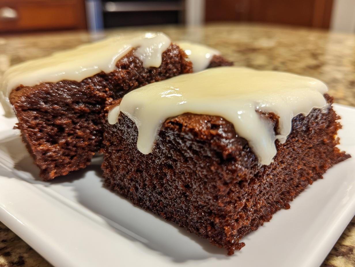 Close-up of two rich, dark gingerbread brownies topped with thick white cream cheese icing.