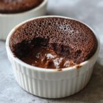 Close-up of a rich chocolate mousse dessert with a molten center served in a white fluted ramekin.