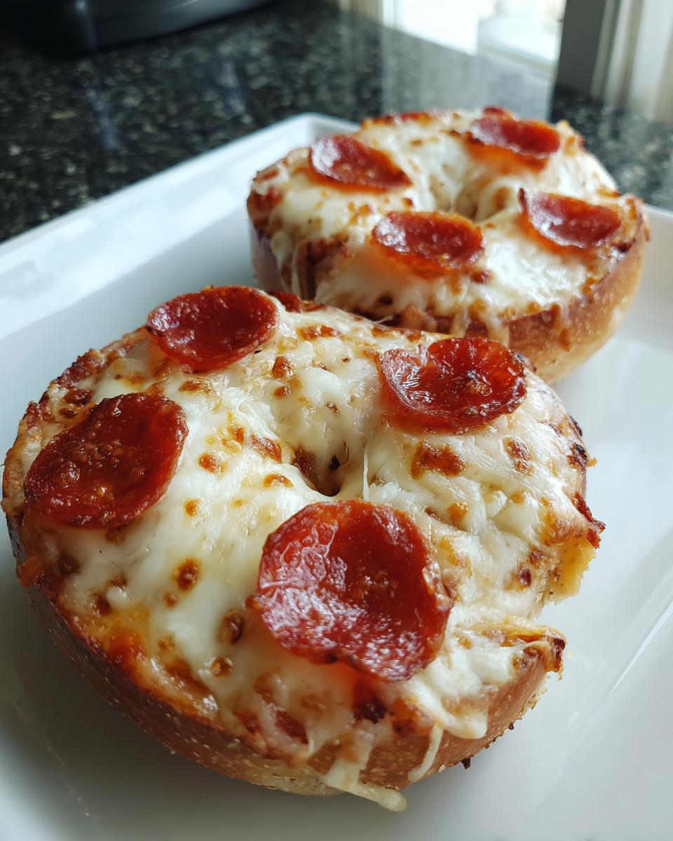 Close-up of two freshly baked pizza bagels topped with melted mozzarella cheese and pepperoni slices.
