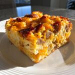 Close-up of a hearty slice of christmas breakfast casserole with sausage and melted cheddar cheese.