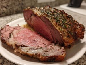 A perfectly cooked standing rib roast, sliced to show medium-rare pink interior and herb crust.