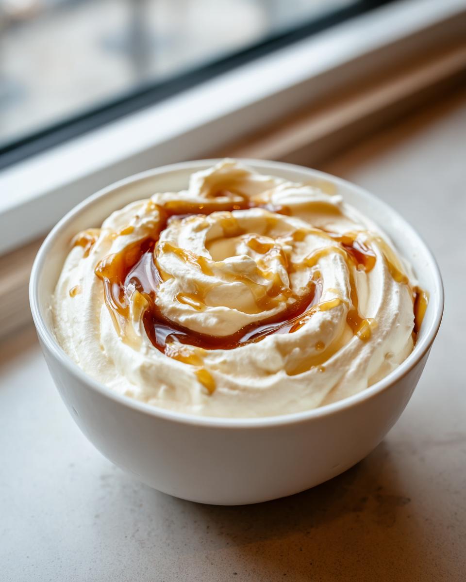 Close-up of creamy whipped ricotta dip swirled high in a white bowl, drizzled with caramel sauce.
