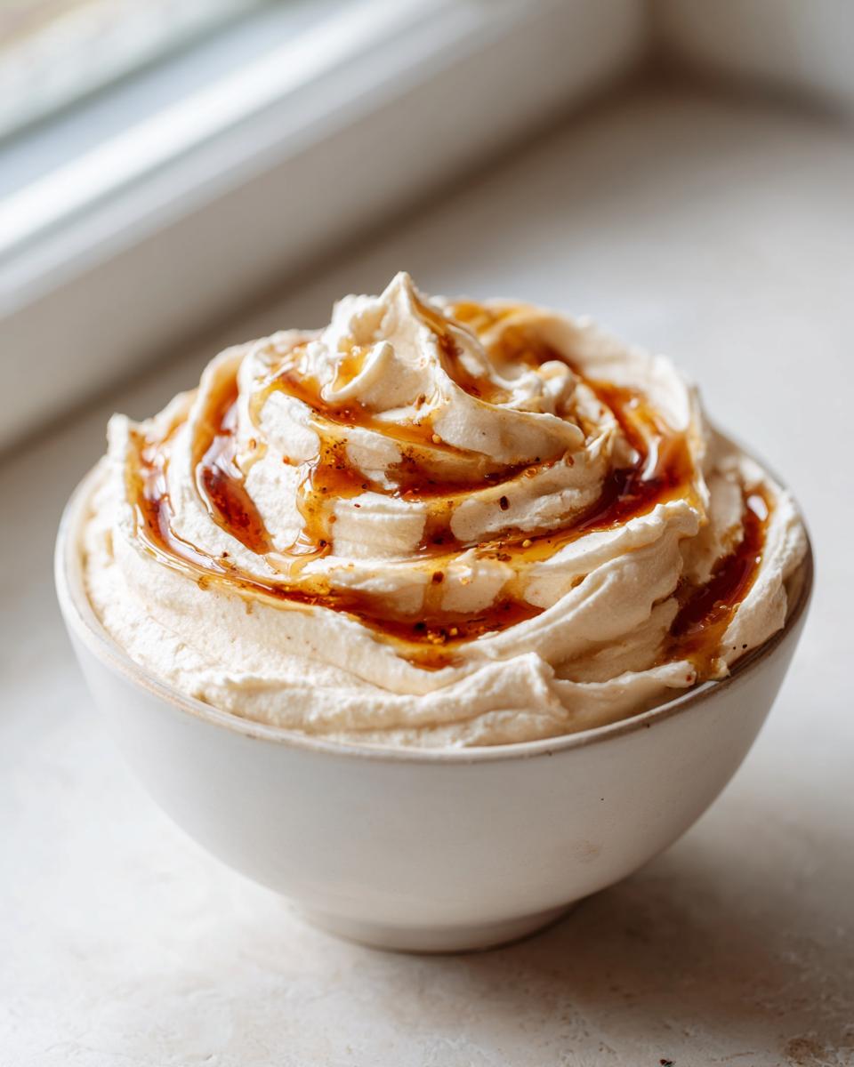 A bowl of creamy whipped ricotta dip topped with a swirl of golden honey or syrup.