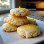 A stack of five soft, melt-in-your-mouth lemon cookies topped with bright yellow glaze and zest.