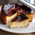 A slice of creamy Basque burnt cheesecake with a dark caramelized top served on a white plate.