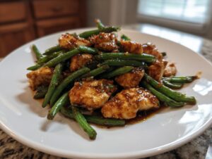 Close-up of bite-sized pieces of glazed chicken mixed with bright green beans, featuring the amazing chicken and green beans dish.