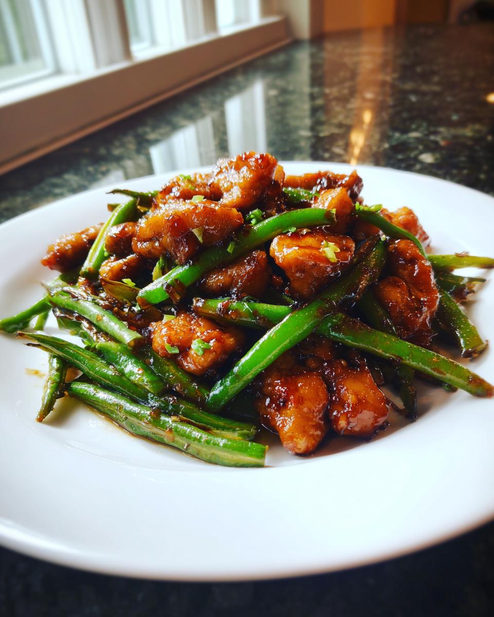 A close-up of a plate featuring glazed chicken and bright green beans, showcasing the amazing chicken and green beans recipe.