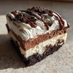 A close-up of a layered slice of Baileys Chocolate Cheesecake Trifle topped with whipped cream and chocolate drizzle.