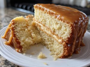 Close-up of a moist slice of Southern caramel cake with thick, dripping caramel frosting.