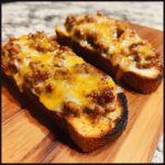 Two slices of toasted bread topped with savory browned meat mixture and melted cheddar cheese, ready to eat as a hanky panky recipe appetizer.