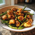 Close-up of glazed chicken pieces mixed with bright green beans, a perfect example of chicken and green beans.