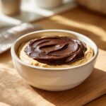 A creamy peanut butter dip topped with a swirl of rich chocolate ganache in a white bowl.