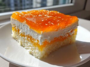 A single, layered slice of Creamsicle Cake featuring a light sponge base, white cream layer, and bright orange gelatin topping.