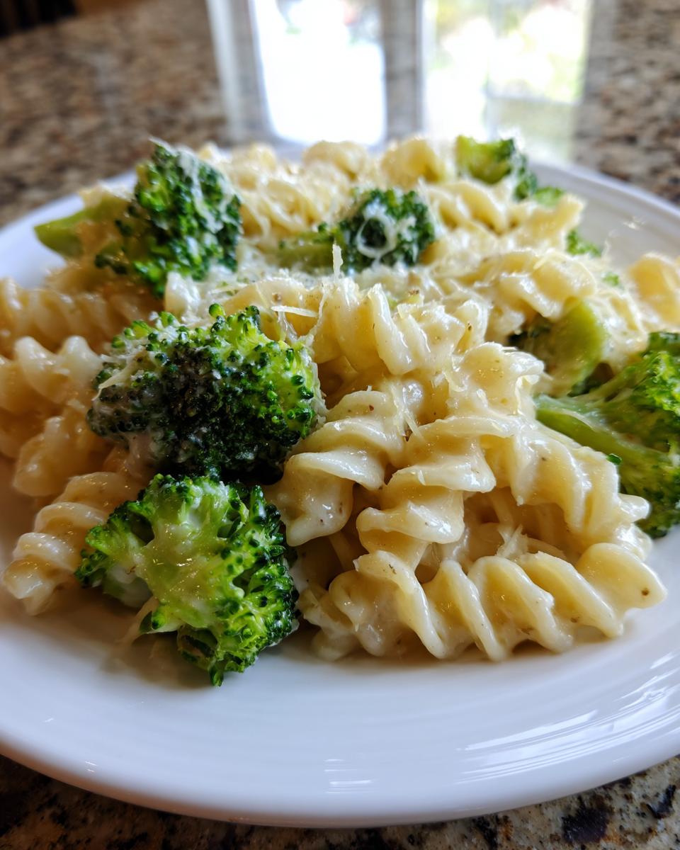 Close-up of creamy broccoli pasta made with fusilli noodles, bright green broccoli florets, and topped with grated Parmesan cheese.