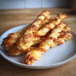 A pile of golden, flaky, twisted cheese straws recipe baked until crispy and golden brown.