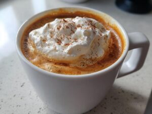 Close-up of a rich, frothy pumpkin spice latte topped with whipped cream and cinnamon.
