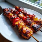 Three grilled chicken skewers loaded with glazed chicken, red peppers, and onions, ready to eat.