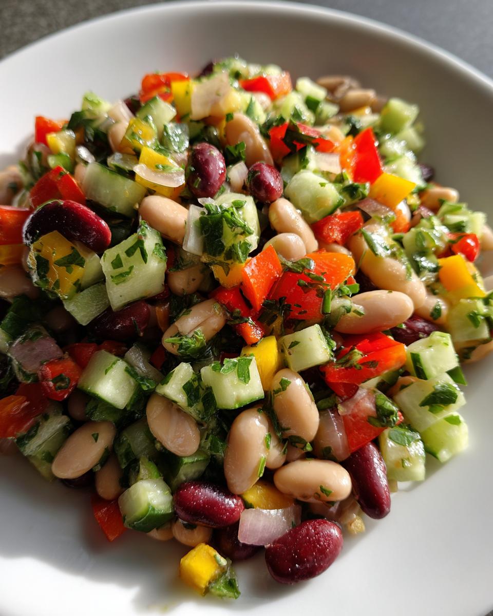 Close-up of a vibrant Mediterranean bean salad featuring cannellini beans, kidney beans, cucumber, and bell peppers.