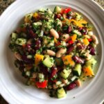 Close-up of a colorful Mediterranean bean salad featuring kidney beans, cannellini beans, cucumber, and bell peppers.