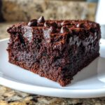 Close-up of a rich, dark chocolate slice of sweet potato brownies topped with chocolate chips.