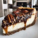A decadent slice of pecan pie cheesecake featuring a thick graham cracker crust and a gooey pecan topping.