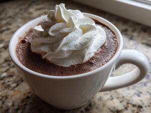 Close-up of a mug filled with rich, dark hot chocolate topped generously with whipped cream.