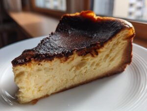 A close-up slice of creamy Basque burnt cheesecake showing the signature dark, caramelized top.